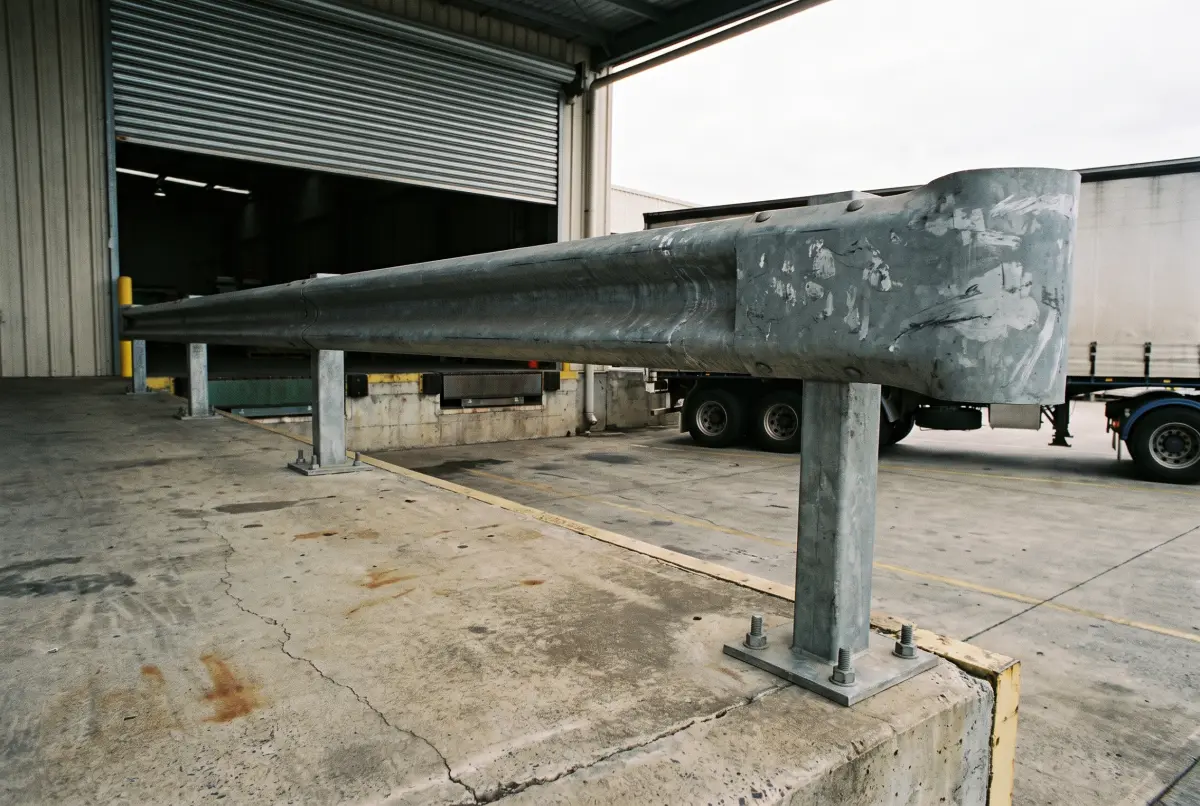 Steel guard rail barrier bolted to the concrete edge of a warehouse loading dock